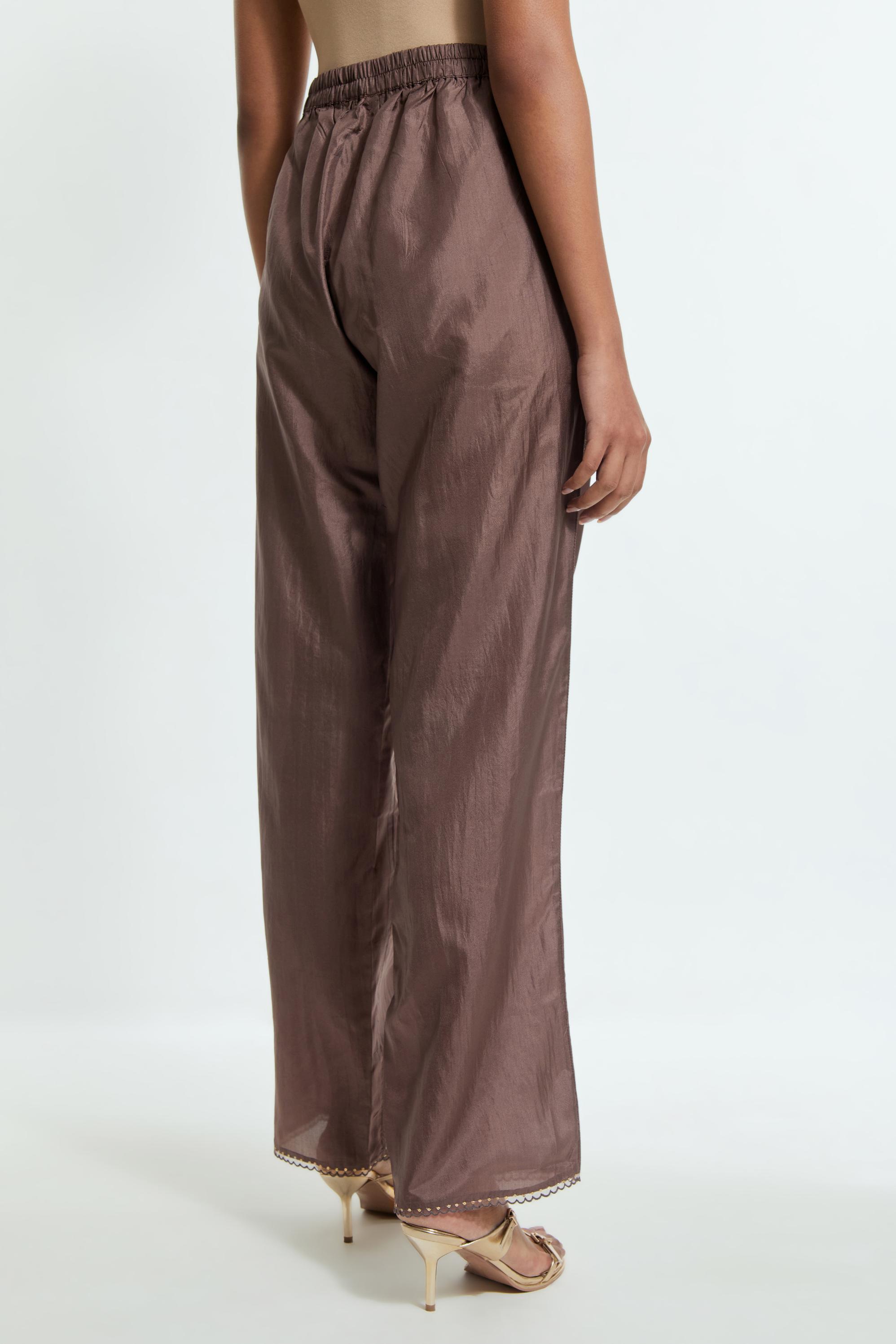 Grey silk straight pants detailed with scalloped organza edging at the hem, delicately highlighted with gold sequins work.