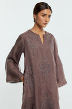 Grey silk organza A-line short kurta adorned with delicately placed floral appliqué motifs and subtle sequin embellishments. Paired with grey silk straight pants detailed with scalloped organza edging at hem, delicately highlighted with gold sequins work.
