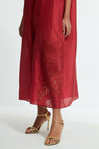 Red silk long dress adorned with appliqué chrysanthemum floral motifs along one side, delicately highlighted with fine French knots and subtle sequins.