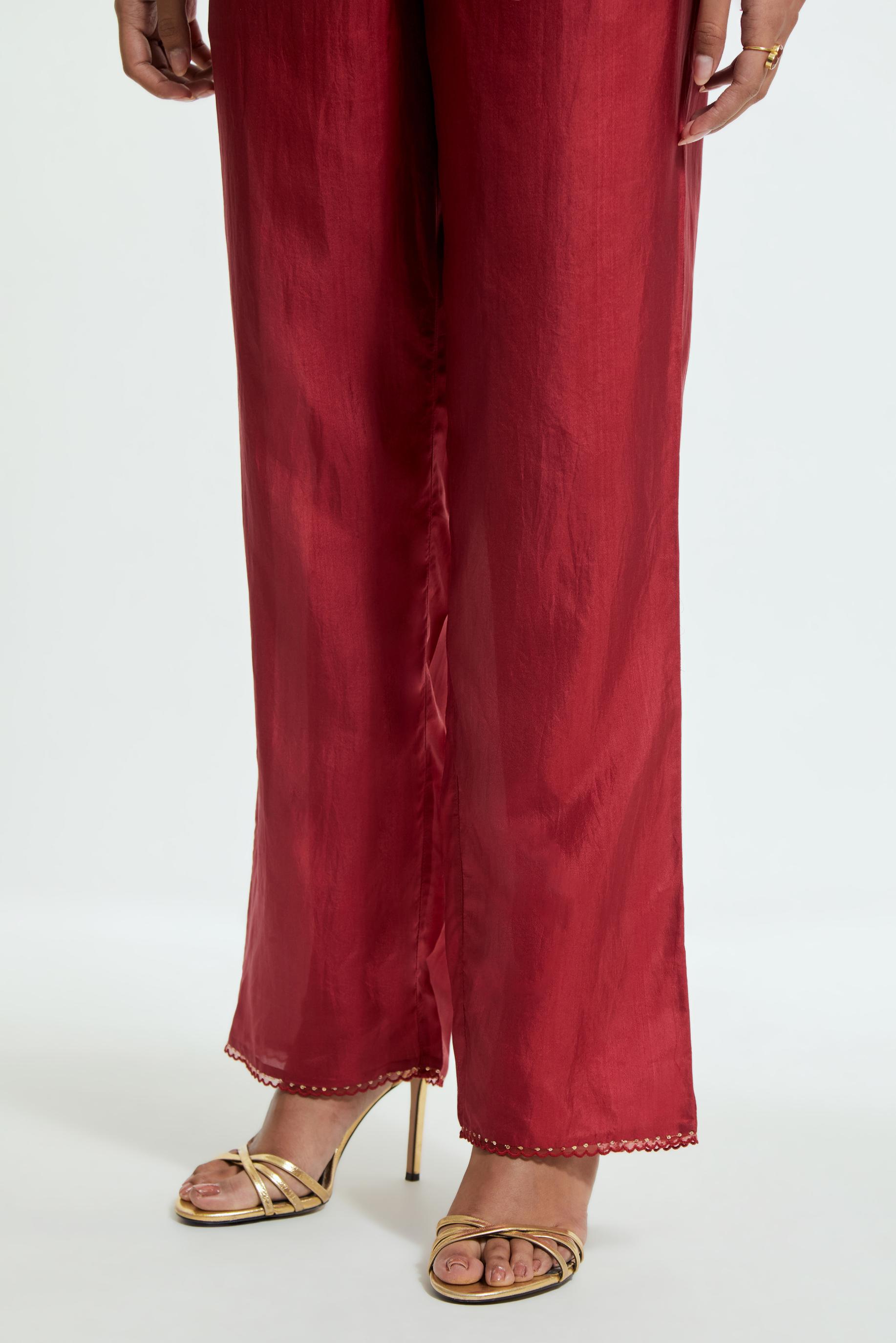 Red silk straight pants detailed with scalloped organza edging at the hem, delicately highlighted with gold sequins work.