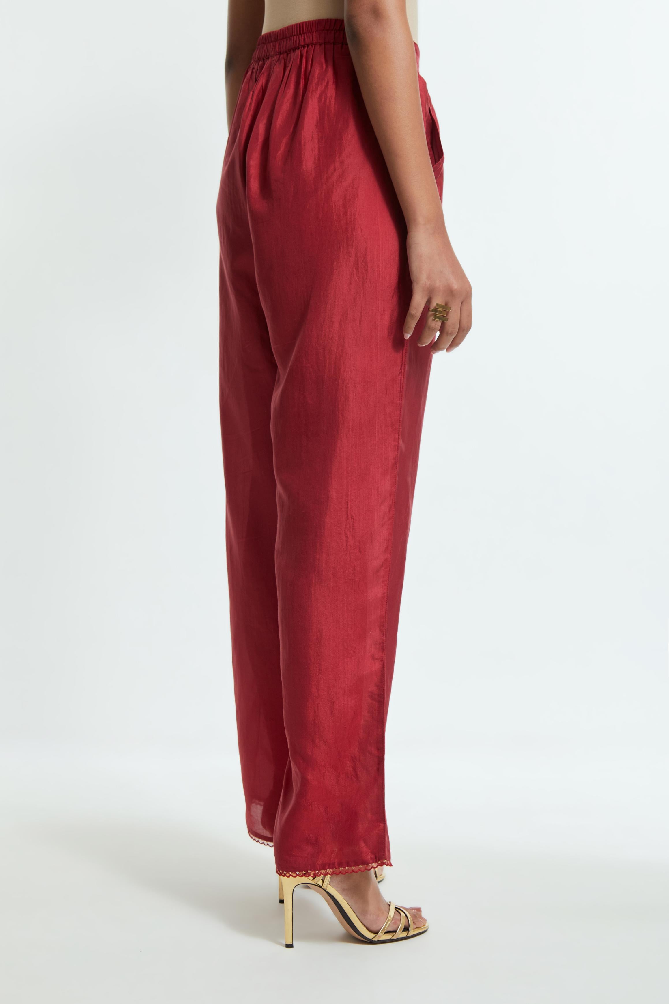 Red silk straight pants detailed with scalloped organza edging at the hem, delicately highlighted with gold sequins work.
