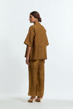 Olive silk organza short top featuring silk appliqué floral motifs and a shirt collar neckline. Paired with Olive silk straight pants detailed with scalloped organza edging at the hem, delicately highlighted with tonal beadwork.