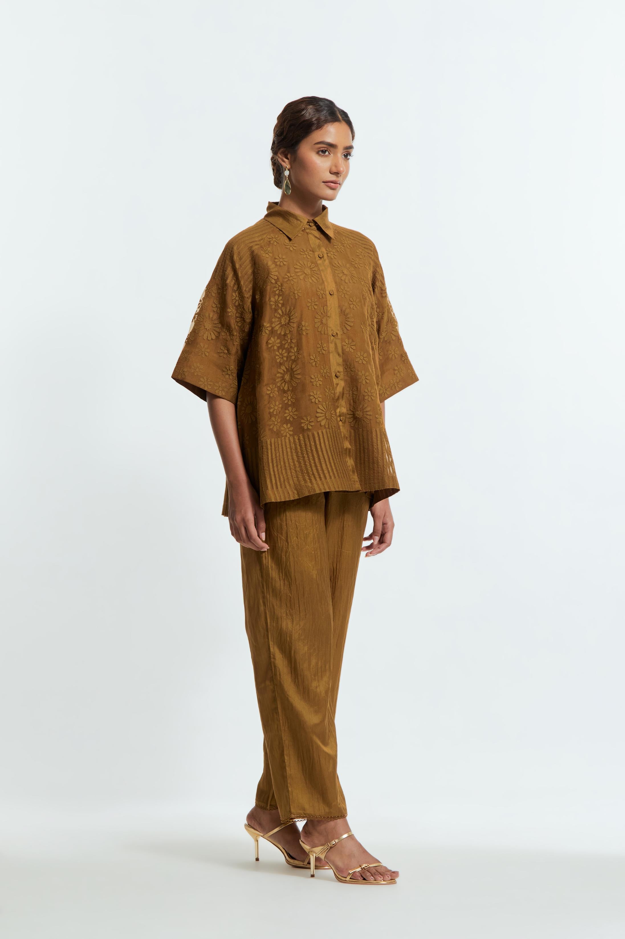 Olive silk organza short top featuring silk appliqué floral motifs and a shirt collar neckline. Paired with Olive silk straight pants detailed with scalloped organza edging at the hem, delicately highlighted with tonal beadwork.