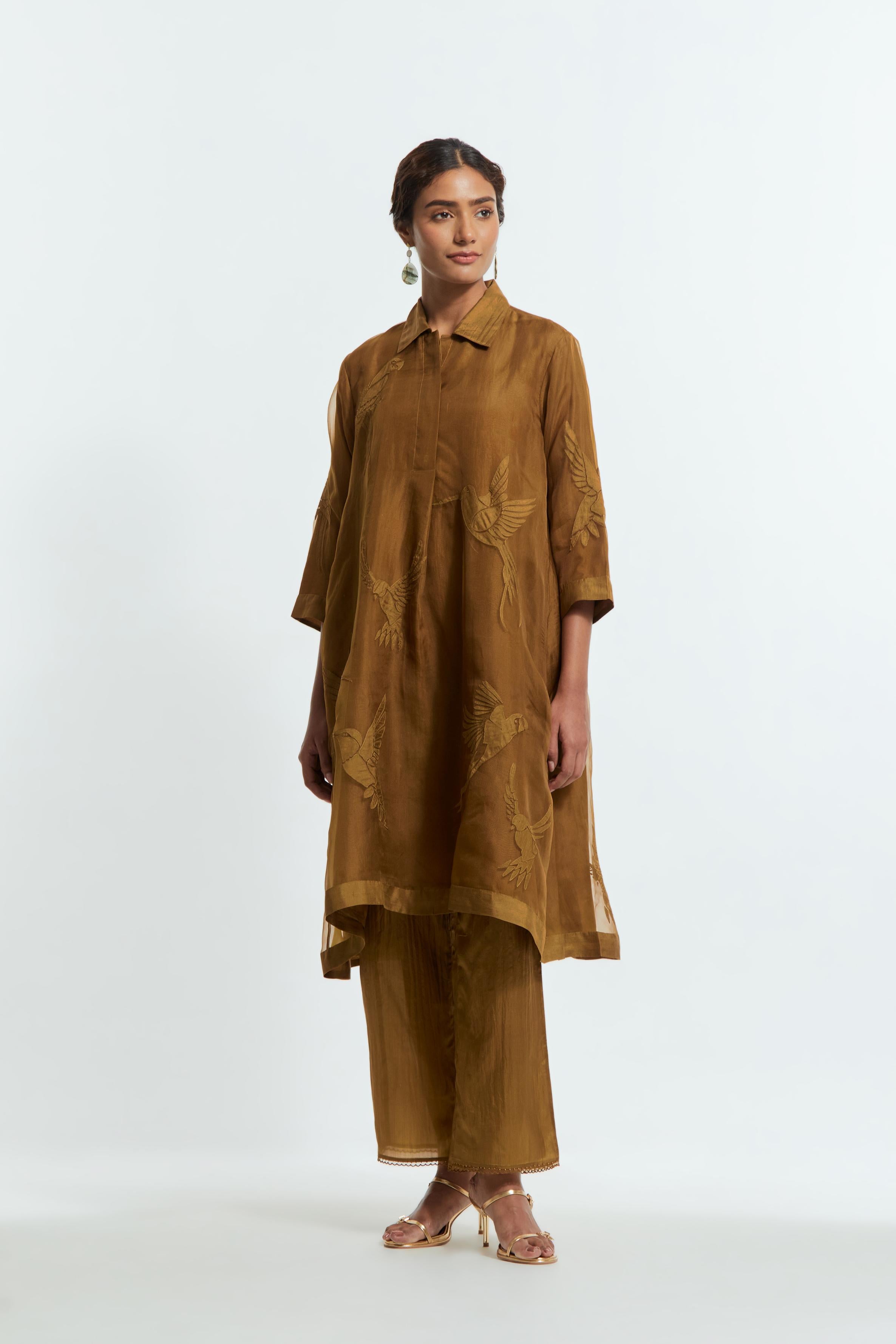 Olive silk organza A-line short kurta featuring appliqué bird motifs gracefully placed across the front, back and sleeves. Paired with Olive silk straight pants detailed with scalloped organza edging at the hem, delicately highlighted with tonal beadwork.