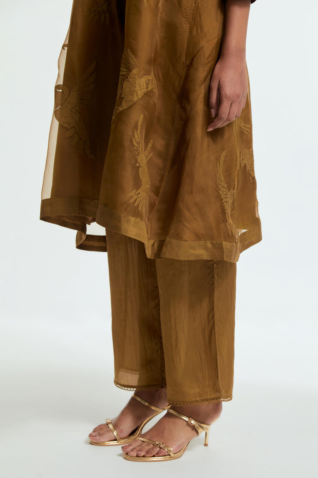 Olive silk organza A-line short kurta featuring appliqué bird motifs gracefully placed across the front, back and sleeves. Paired with Olive silk straight pants detailed with scalloped organza edging at the hem, delicately highlighted with tonal beadwork.