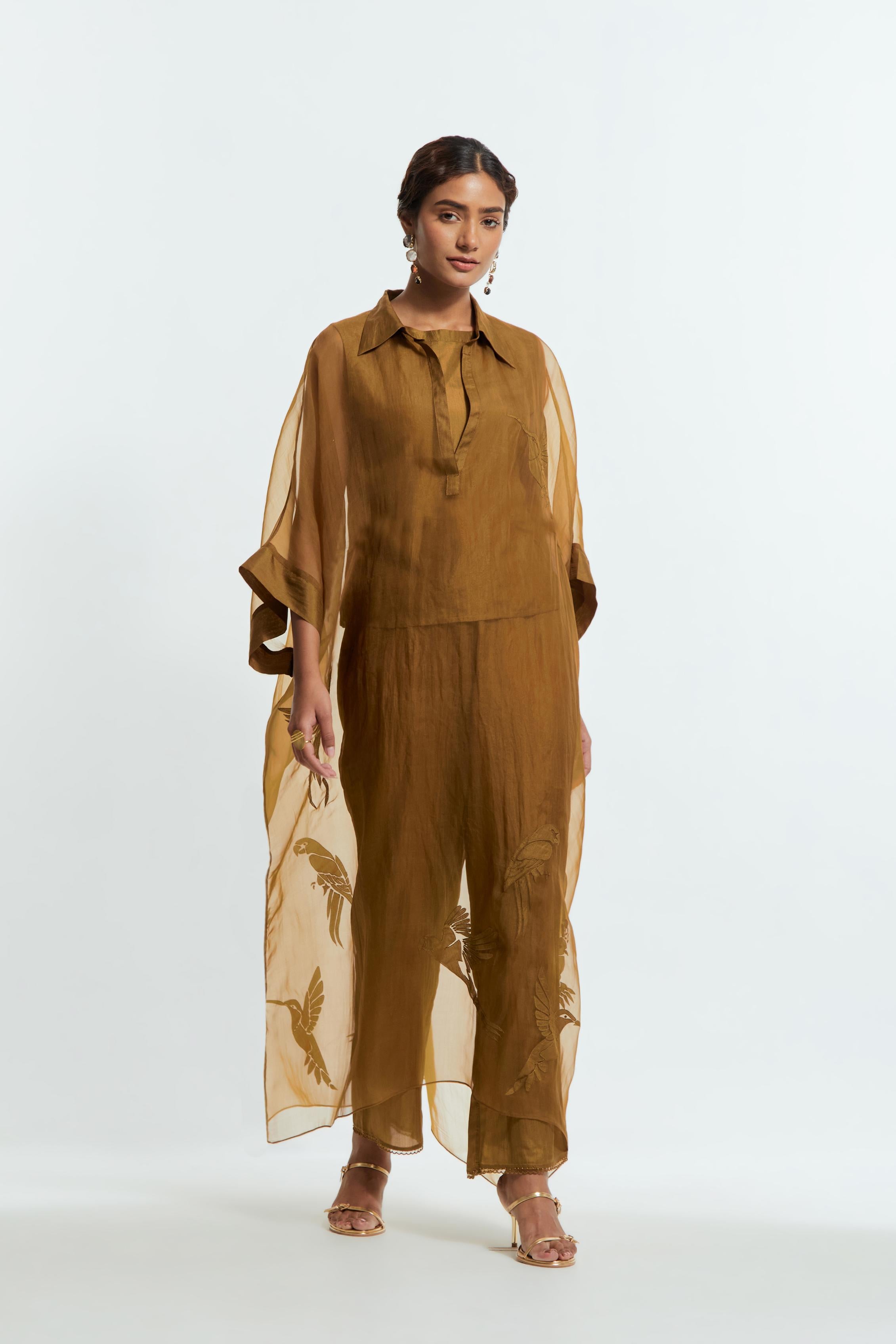 Olive silk organza kaftan with a sheer finish, delicately adorned with appliqué bird motifs along the hem and sides. Paired with Olive silk straight pants detailed with scalloped organza edging at the hem, delicately highlighted with tonal beadwork.