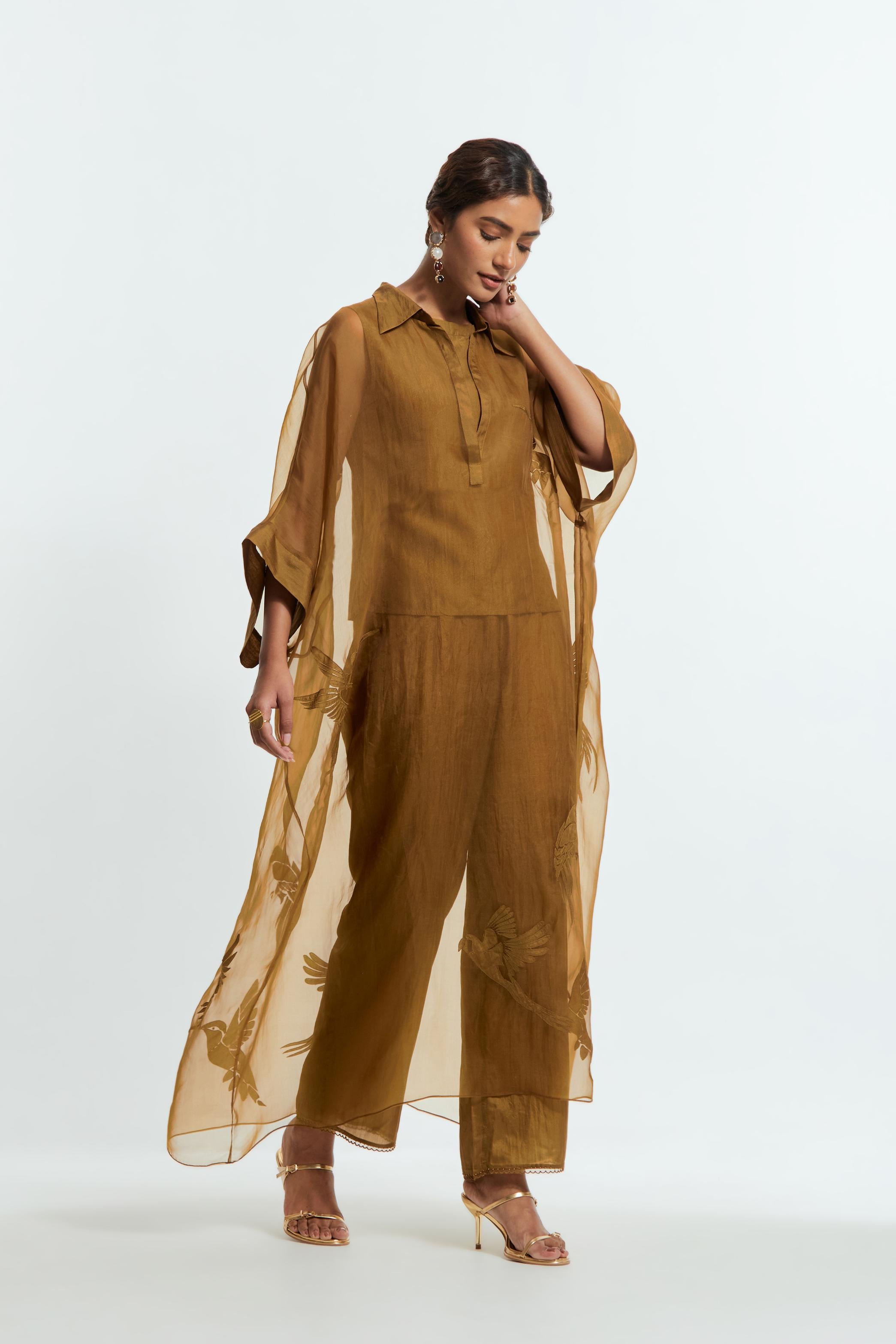 Olive silk organza kaftan with a sheer finish, delicately adorned with appliqué bird motifs along the hem and sides. Paired with Olive silk straight pants detailed with scalloped organza edging at the hem, delicately highlighted with tonal beadwork.