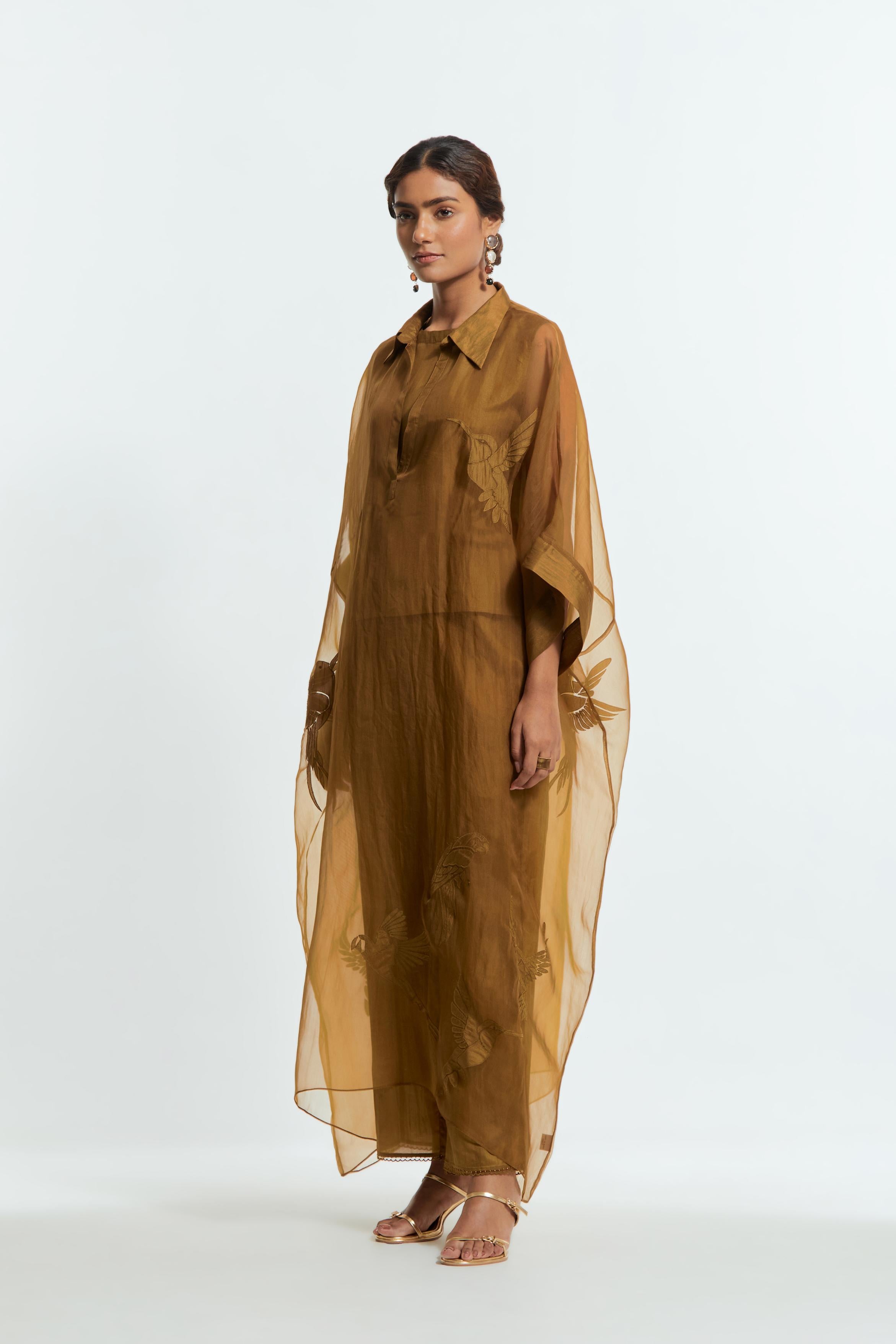 Olive silk organza kaftan with a sheer finish, delicately adorned with appliqué bird motifs along the hem and sides. Paired with Olive silk straight pants detailed with scalloped organza edging at the hem, delicately highlighted with tonal beadwork.
