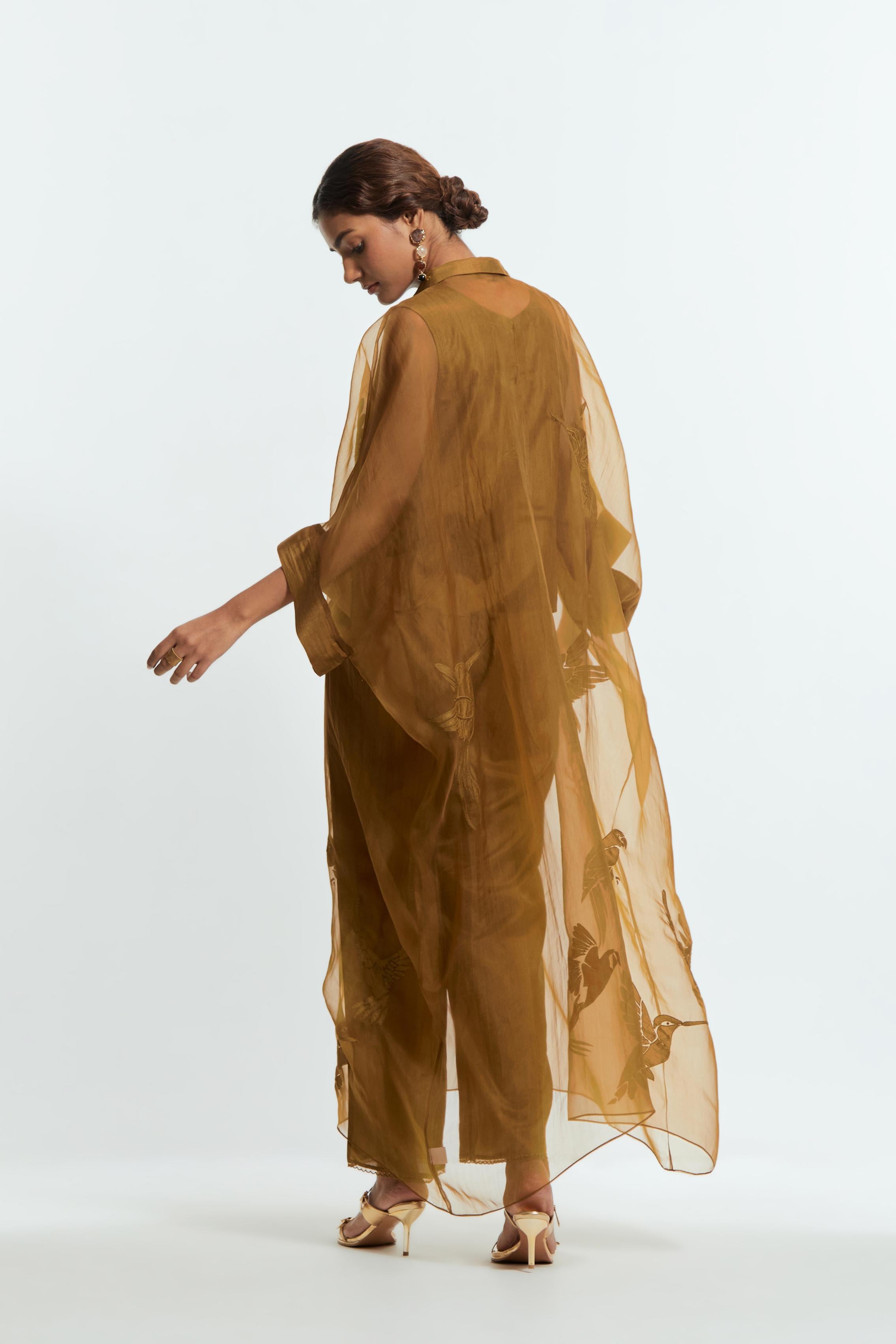 Olive silk organza kaftan with a sheer finish, delicately adorned with appliqué bird motifs along the hem and sides. Paired with Olive silk straight pants detailed with scalloped organza edging at the hem, delicately highlighted with tonal beadwork.