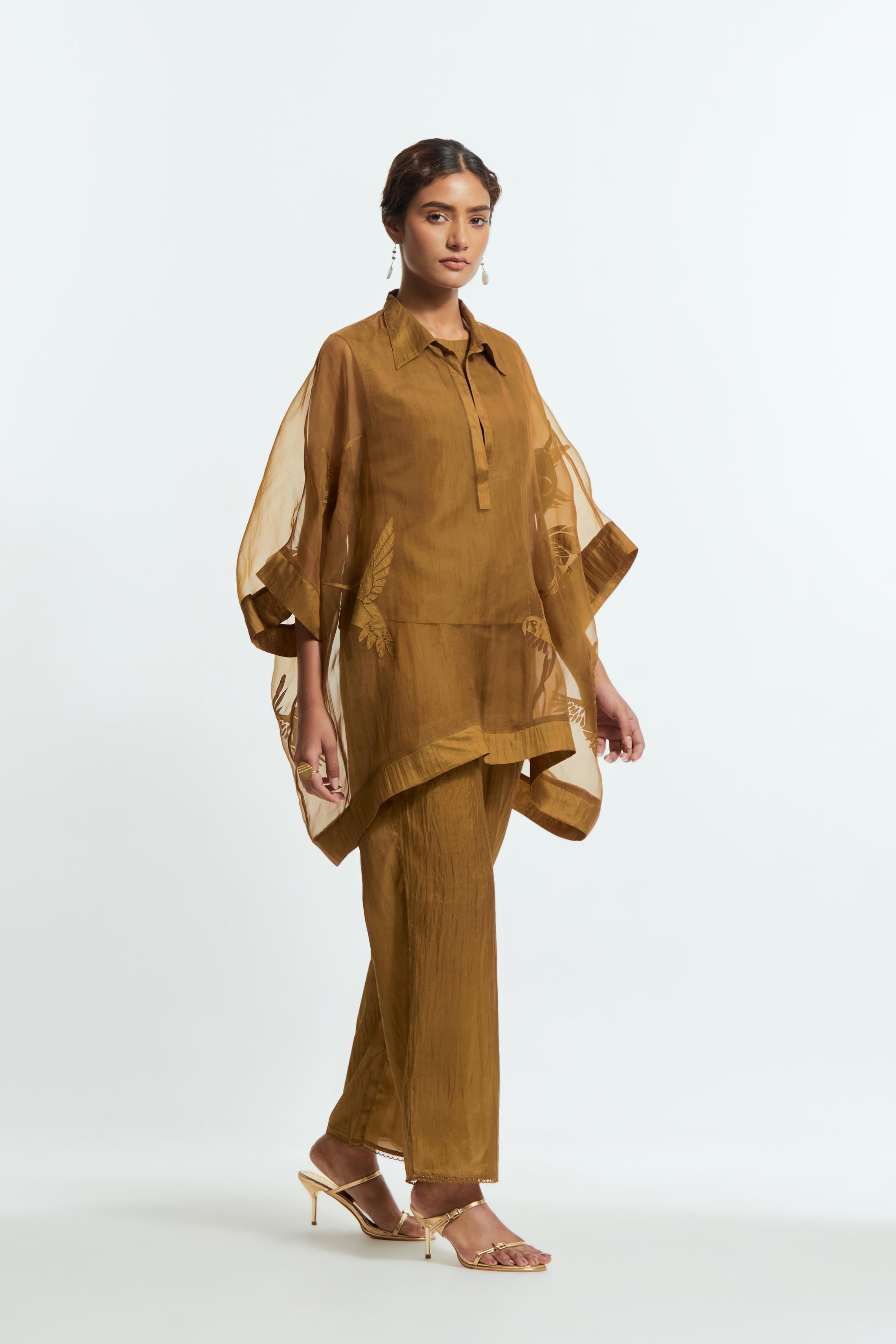 Olive silk organza short kaftan top with a sheer finish, delicately adorned with appliqué bird motifs along the hem and sides. Paired with olive silk straight pants detailed with scalloped organza edging at hem, delicately highlighted with tonal beadwork.