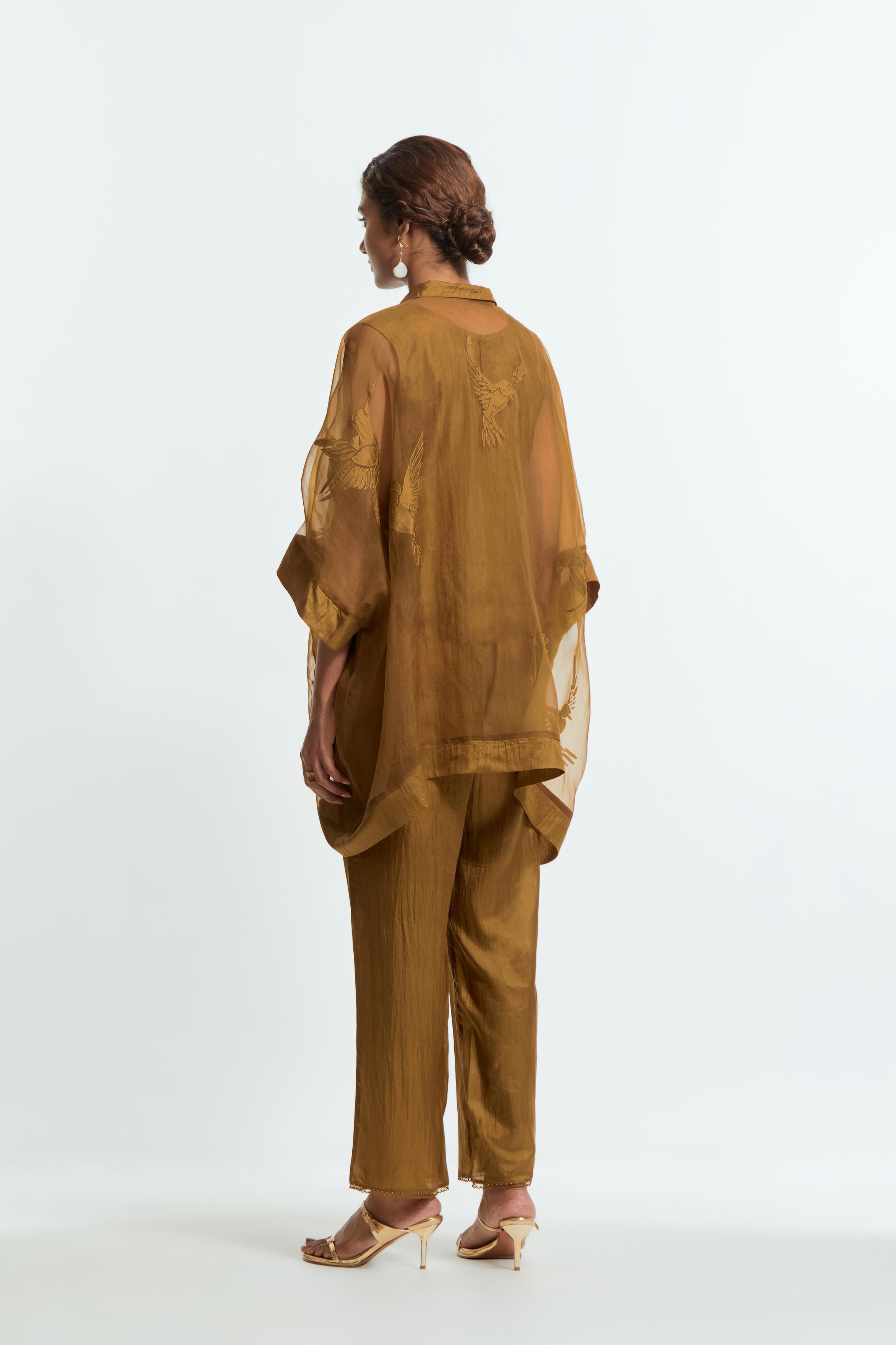 Olive silk organza short kaftan top with a sheer finish, delicately adorned with appliqué bird motifs along the hem and sides. Paired with olive silk straight pants detailed with scalloped organza edging at hem, delicately highlighted with tonal beadwork.
