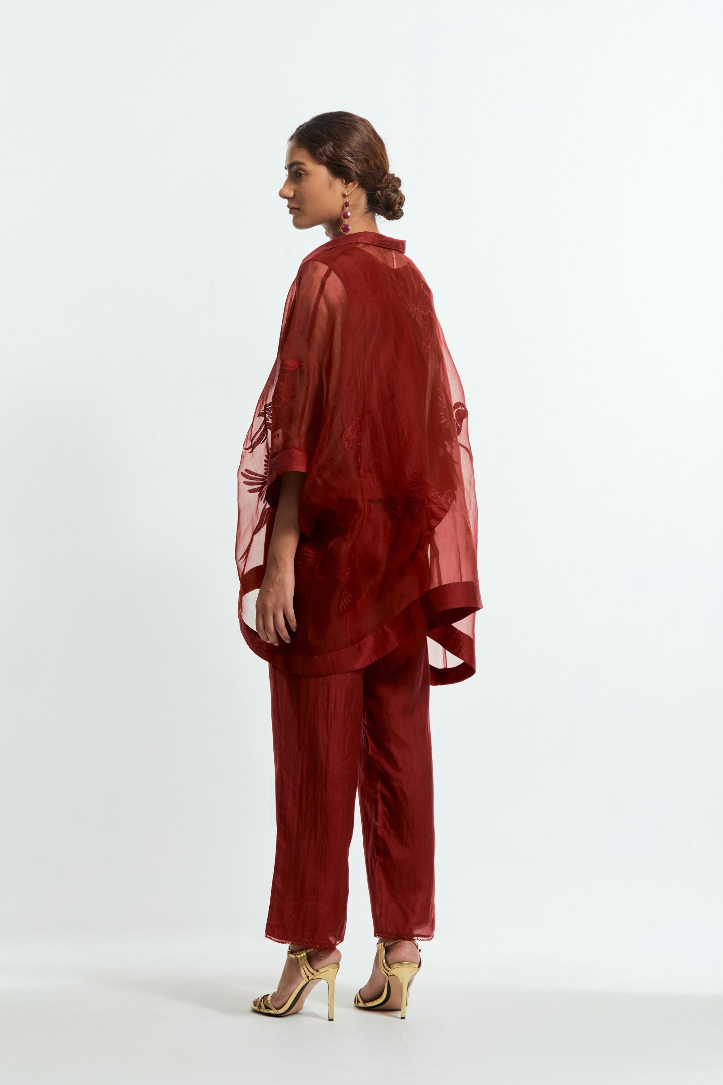 Red silk organza short kaftan top with a sheer finish, delicately adorned with appliqué bird motifs along the hem and sides. Paired with Red silk straight pants detailed with scalloped organza edging at the hem, delicately highlighted with tonal beadwork.