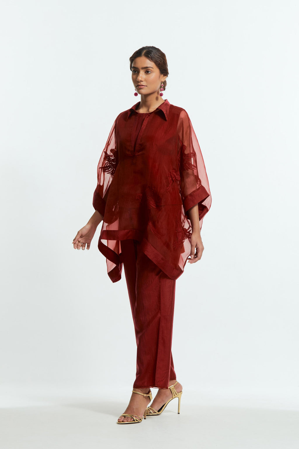 Red silk organza short kaftan top with a sheer finish, delicately adorned with appliqué bird motifs along the hem and sides. Paired with Red silk straight pants detailed with scalloped organza edging at the hem, delicately highlighted with tonal beadwork.