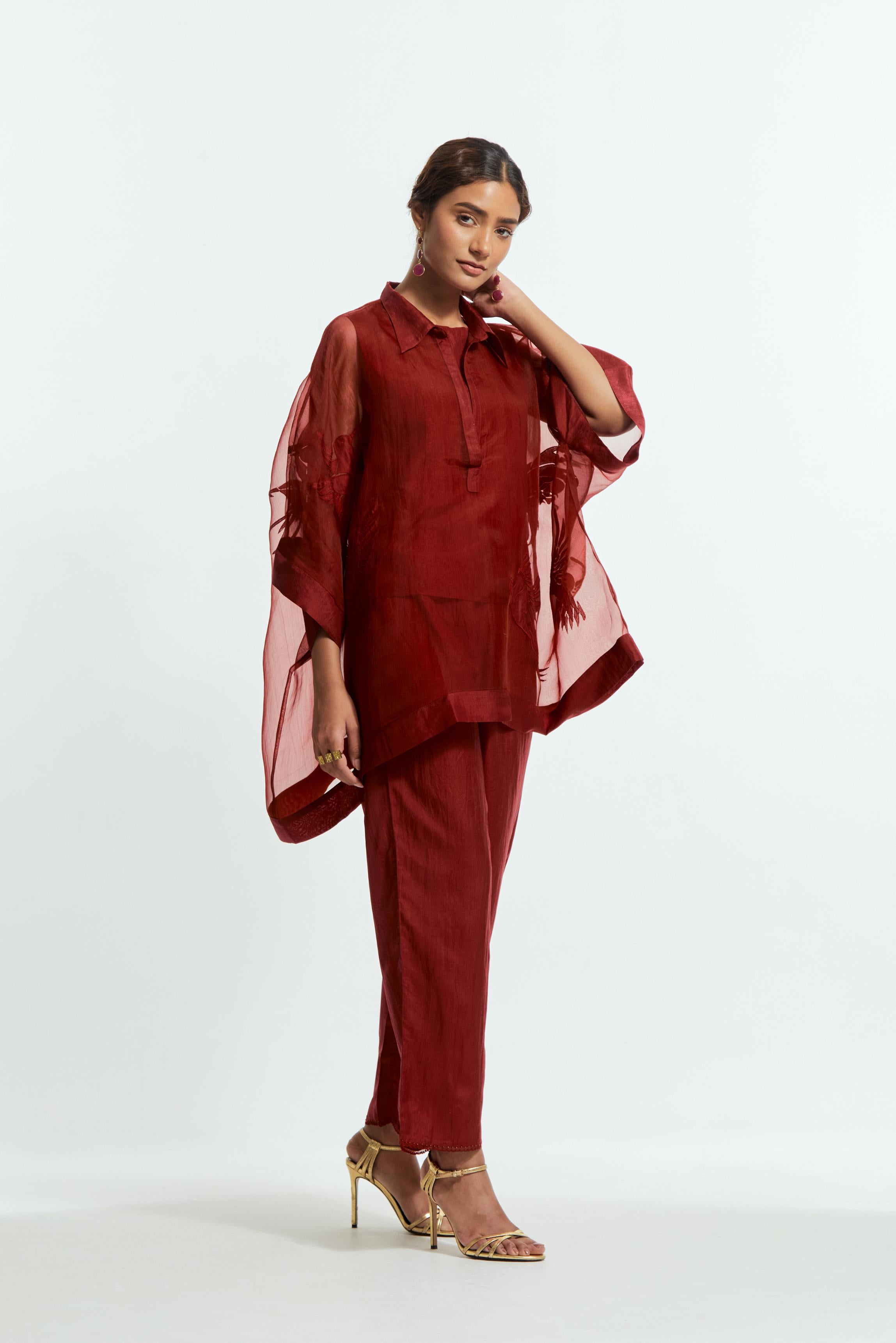 Red silk organza short kaftan top with a sheer finish, delicately adorned with appliqué bird motifs along the hem and sides. Paired with Red silk straight pants detailed with scalloped organza edging at the hem, delicately highlighted with tonal beadwork.