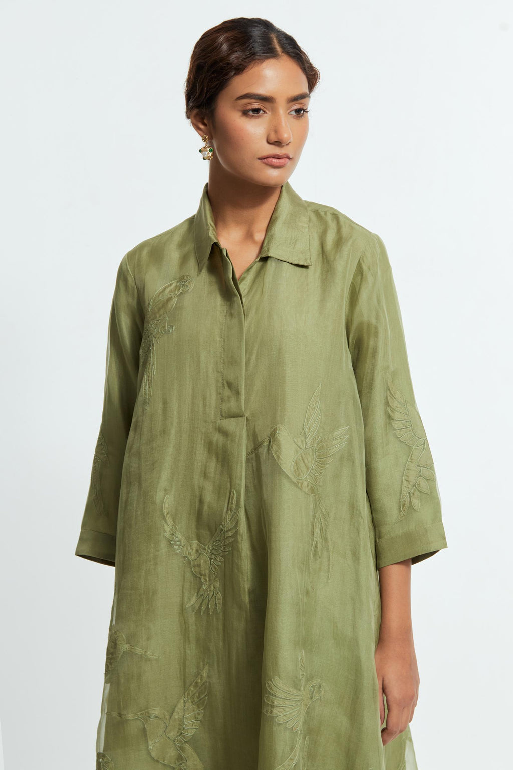 Green silk organza A-line short kurta featuring appliqué bird motifs gracefully placed across the front, back and sleeves. Paired with Green silk straight pants detailed with scalloped organza edging at the hem, delicately highlighted with tonal beadwork.