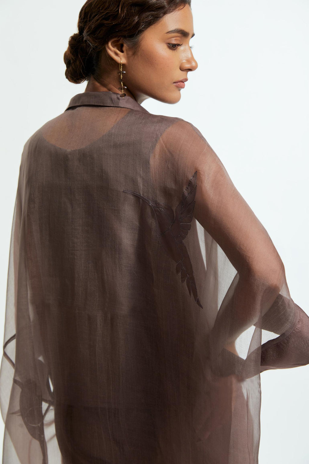 Grey silk organza kaftan with a sheer finish, delicately adorned with appliqué bird motifs along the hem and sides. Paired with Grey silk straight pants detailed with scalloped organza edging at the hem, delicately highlighted with tonal beadwork.