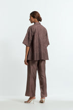 Grey silk organza short top featuring silk appliqué floral motifs and a shirt collar neckline. Paired with Grey silk straight pants detailed with scalloped organza edging at the hem, delicately highlighted with tonal beadwork.