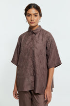 Grey silk organza short top featuring silk appliqué floral motifs and a shirt collar neckline. Paired with Grey silk straight pants detailed with scalloped organza edging at the hem, delicately highlighted with tonal beadwork.