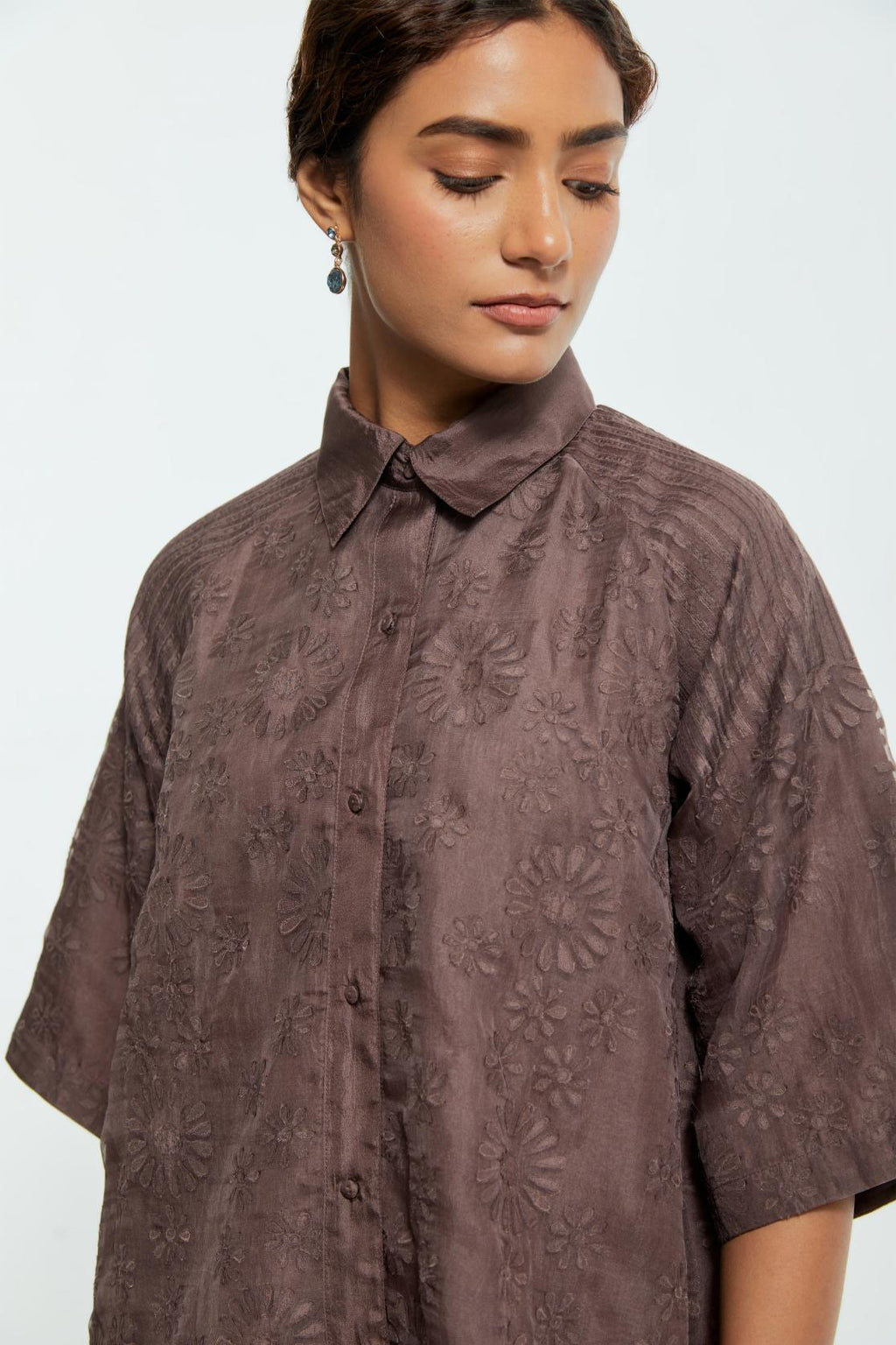 Grey silk organza short top featuring silk appliqué floral motifs and a shirt collar neckline. Paired with Grey silk straight pants detailed with scalloped organza edging at the hem, delicately highlighted with tonal beadwork.