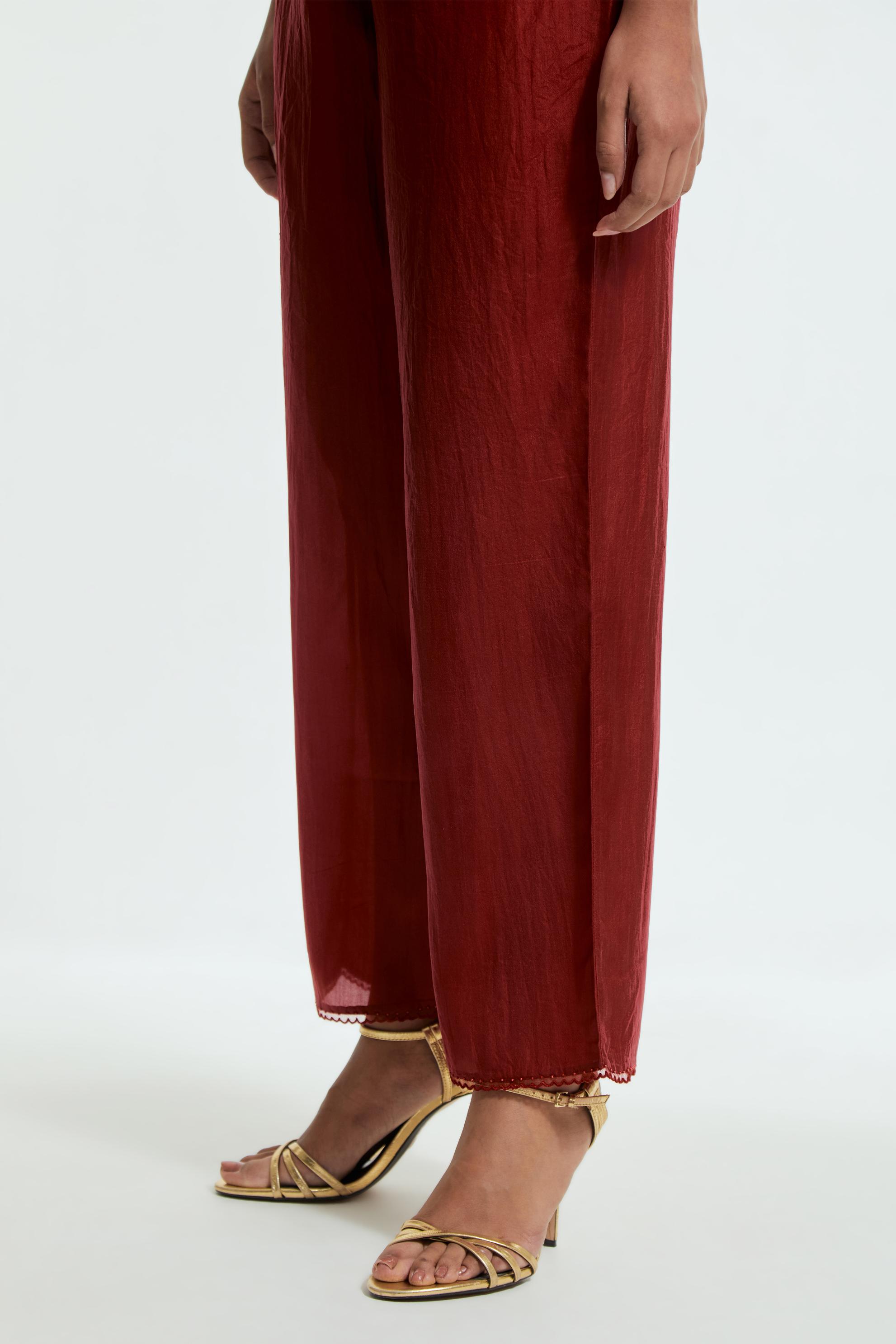 Red silk straight pants detailed with scalloped organza edging at the hem, delicately highlighted with tonal beadwork.