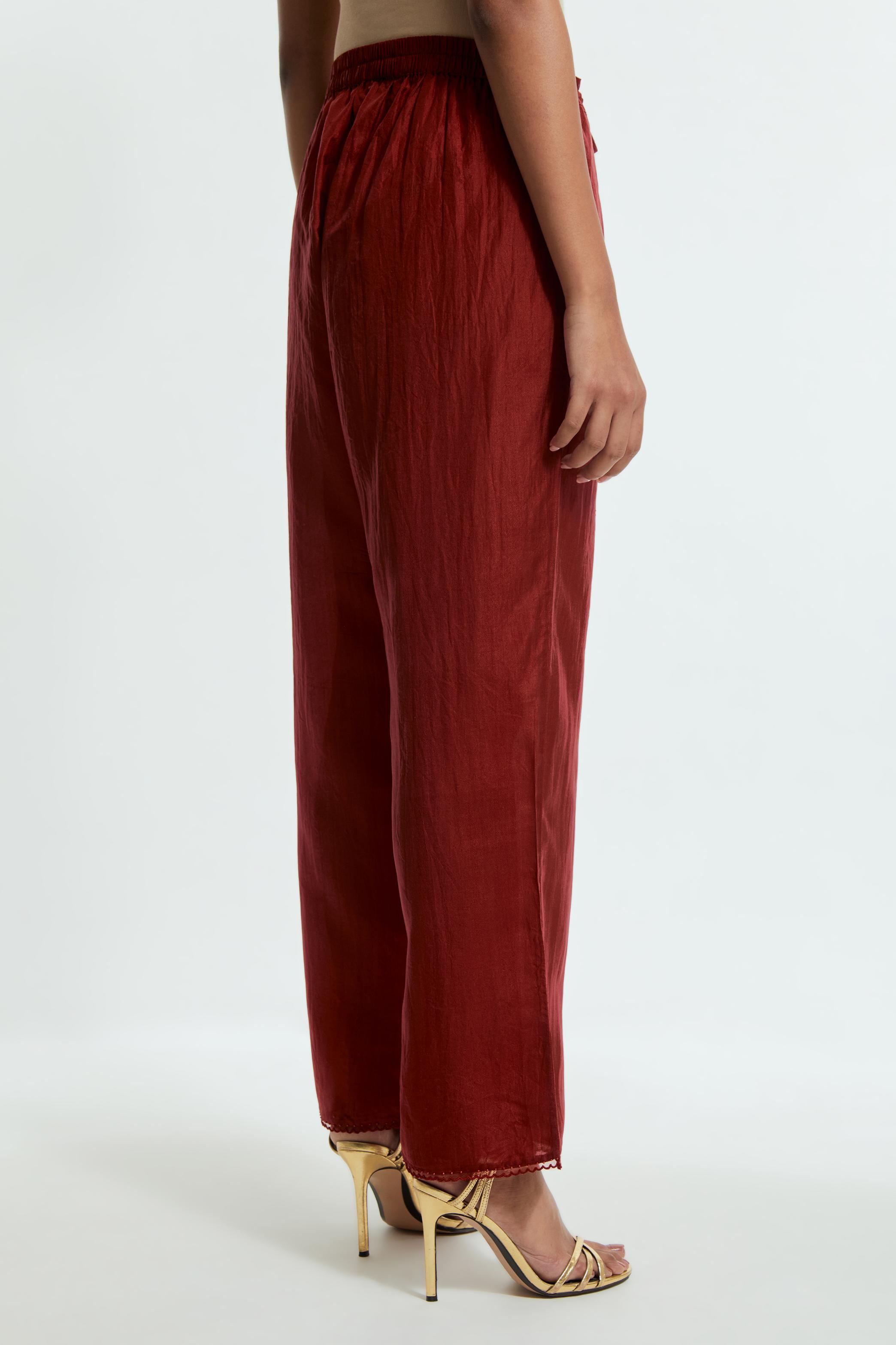 Red silk straight pants detailed with scalloped organza edging at the hem, delicately highlighted with tonal beadwork.