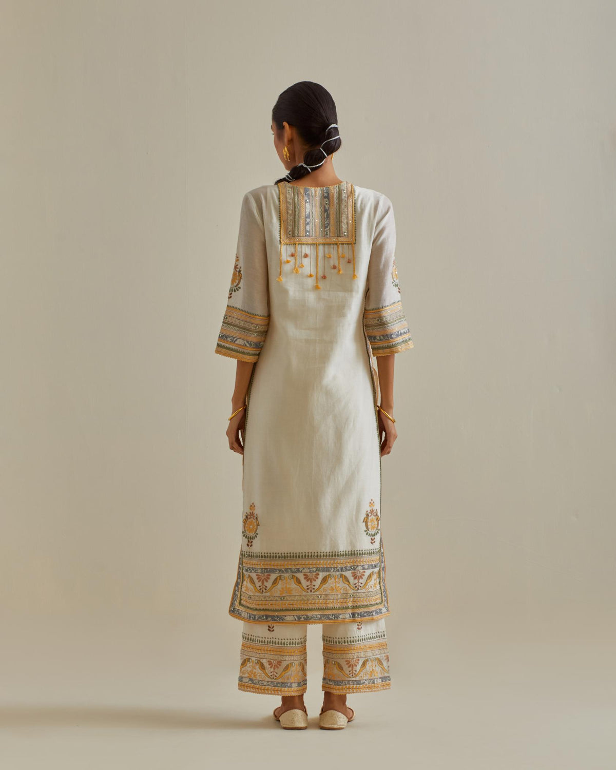 Yellow and off-white cotton chanderi straight kurta set with yoke with patchwork and silk thread embroidery highlighted with mirror, sequins, tassels and braids.