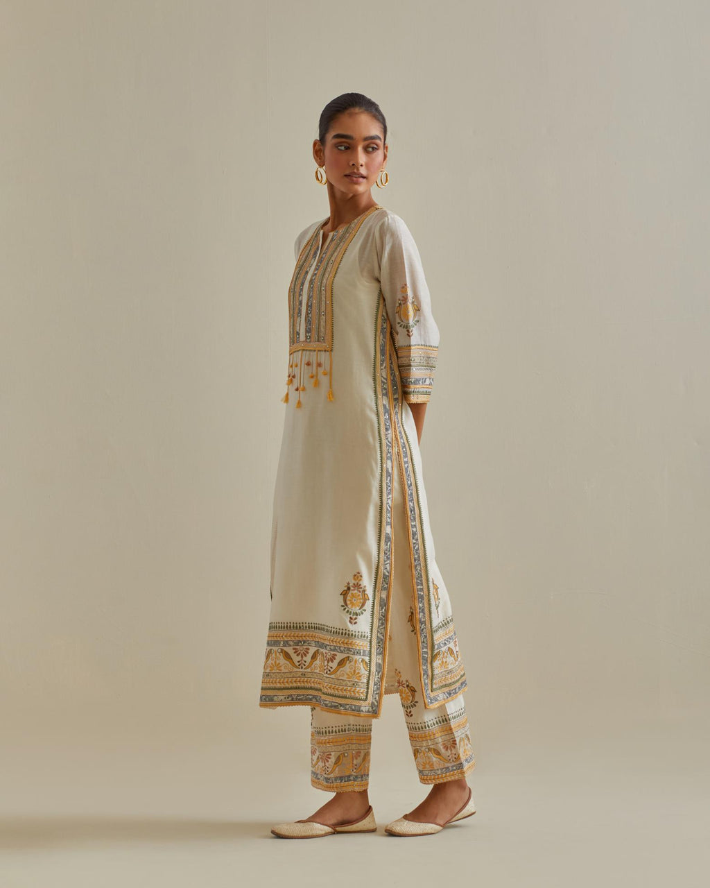 Yellow and off-white cotton chanderi straight kurta set with yoke with patchwork and silk thread embroidery highlighted with mirror, sequins, tassels and braids.