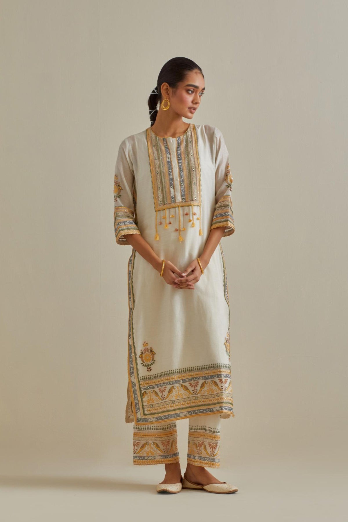 Yellow and off-white cotton chanderi straight kurta set with yoke with patchwork and silk thread embroidery highlighted with mirror, sequins, tassels and braids.