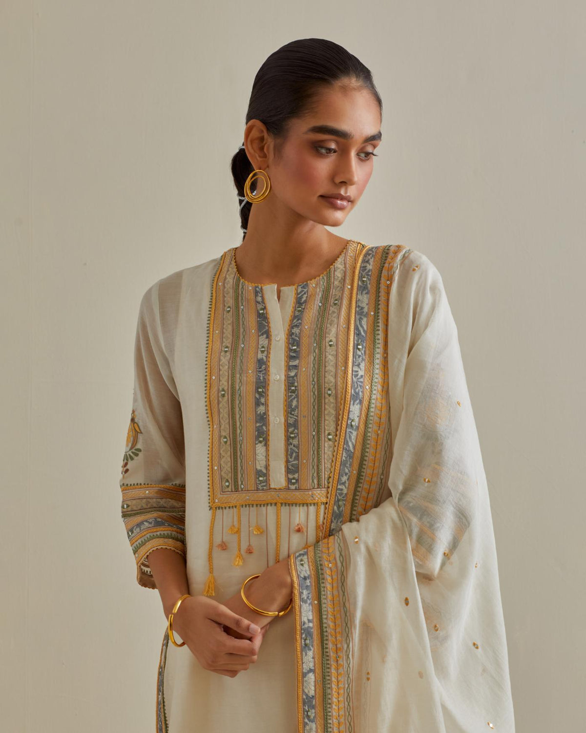 Yellow and off-white cotton chanderi straight kurta set with yoke with patchwork and silk thread embroidery highlighted with mirror, sequins, tassels and braids.