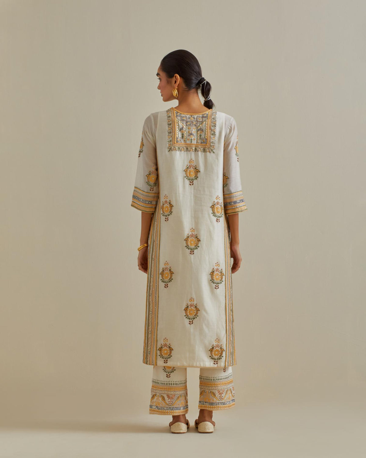 Yellow and off-white cotton chanderi straight kurta set with yoke and side panels. It has allover patchwork and silk thread embroidery, highlighted with mirror, sequins, tassels and braids.