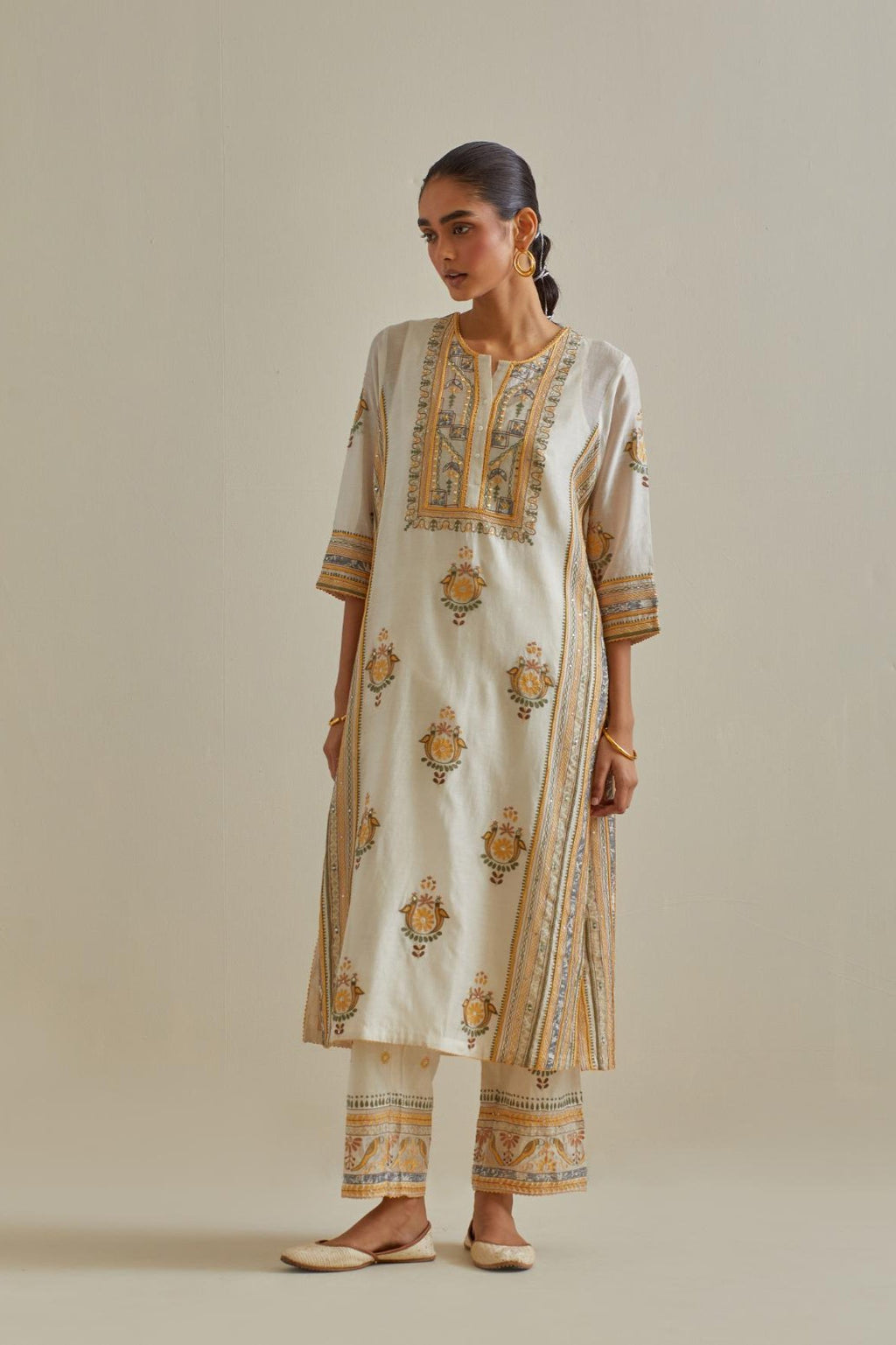 Yellow and off-white cotton chanderi straight kurta set with yoke and side panels. It has allover patchwork and silk thread embroidery, highlighted with mirror, sequins, tassels and braids.