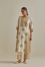 Yellow and off-white cotton chanderi straight kurta set with yoke and side panels. It has allover patchwork and silk thread embroidery, highlighted with mirror, sequins, tassels and braids.