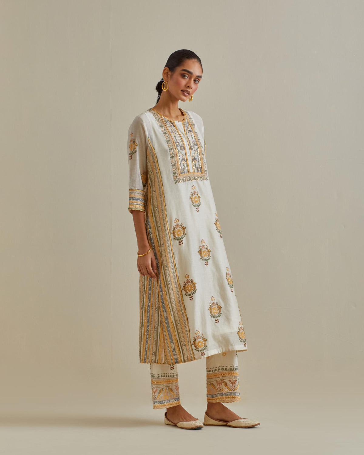 Yellow and off-white cotton chanderi straight kurta set with yoke and side panels. It has allover patchwork and silk thread embroidery, highlighted with mirror, sequins, tassels and braids.