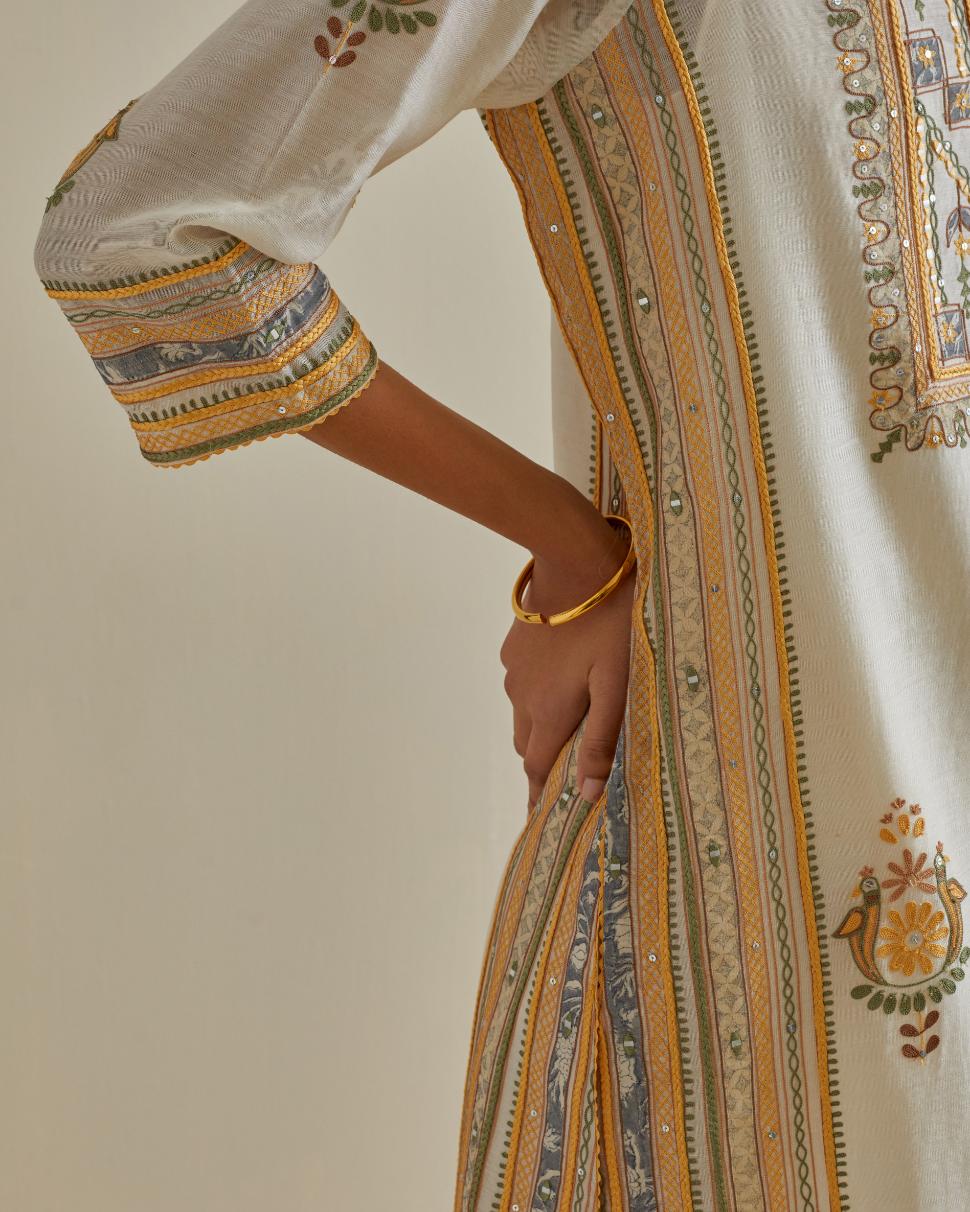Yellow and off-white cotton chanderi straight kurta set with yoke and side panels. It has allover patchwork and silk thread embroidery, highlighted with mirror, sequins, tassels and braids.