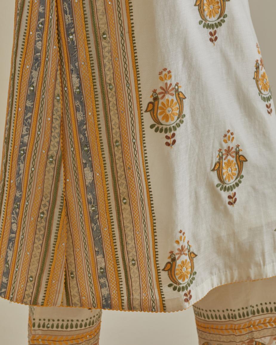 Yellow and off-white cotton chanderi straight kurta set with yoke and side panels. It has allover patchwork and silk thread embroidery, highlighted with mirror, sequins, tassels and braids.