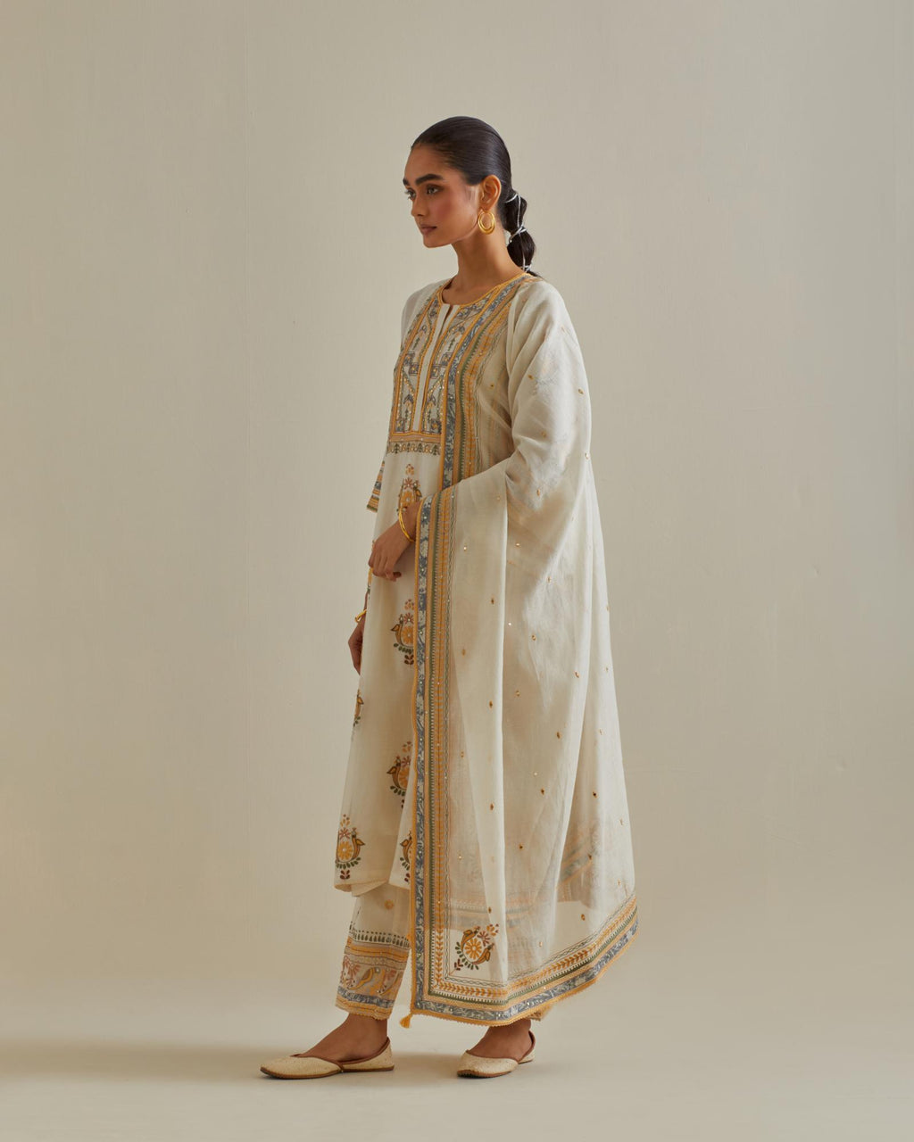 Yellow and off-white cotton chanderi straight kurta set with yoke and side panels. It has allover patchwork and silk thread embroidery, highlighted with mirror, sequins, tassels and braids.
