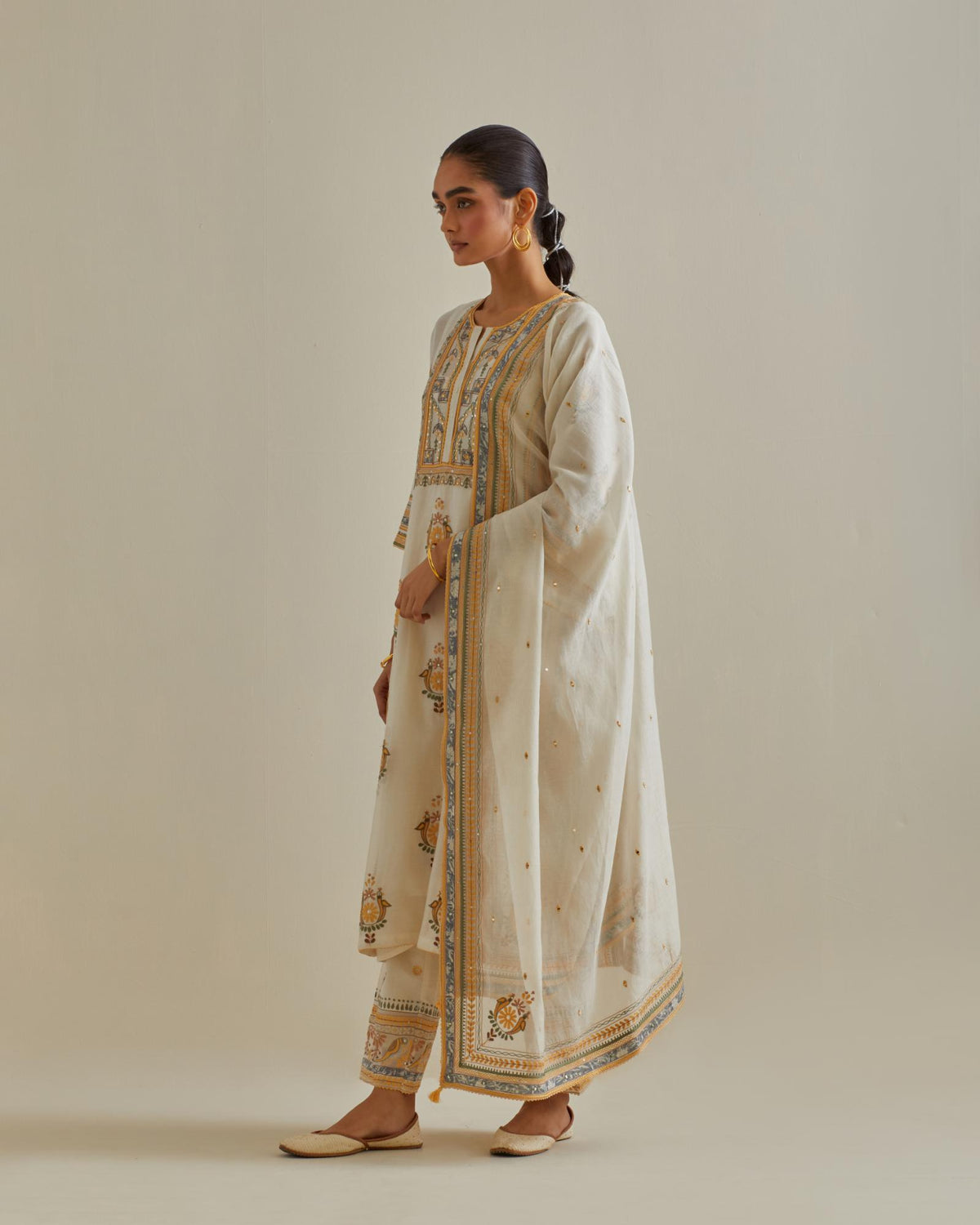 Yellow and off-white cotton chanderi straight kurta set with yoke and side panels. It has allover patchwork and silk thread embroidery, highlighted with mirror, sequins, tassels and braids.