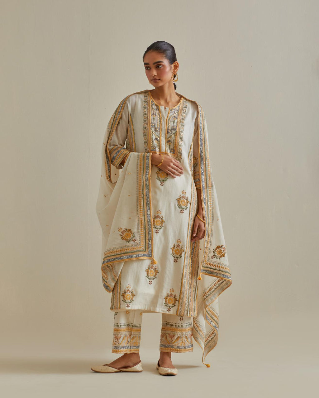 Yellow and off-white cotton chanderi straight kurta set with yoke and side panels. It has allover patchwork and silk thread embroidery, highlighted with mirror, sequins, tassels and braids.