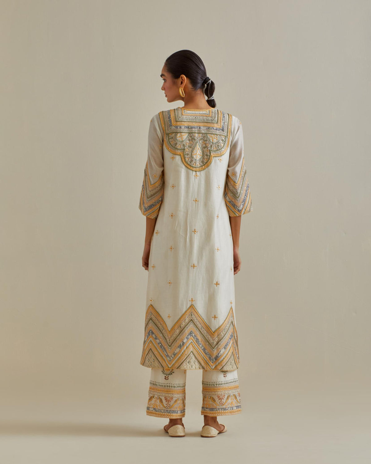 Yellow and off-white cotton chanderi straight kurta set with patchwork and thread embroidery highlighted with mirrors, sequins, tassels and braids.