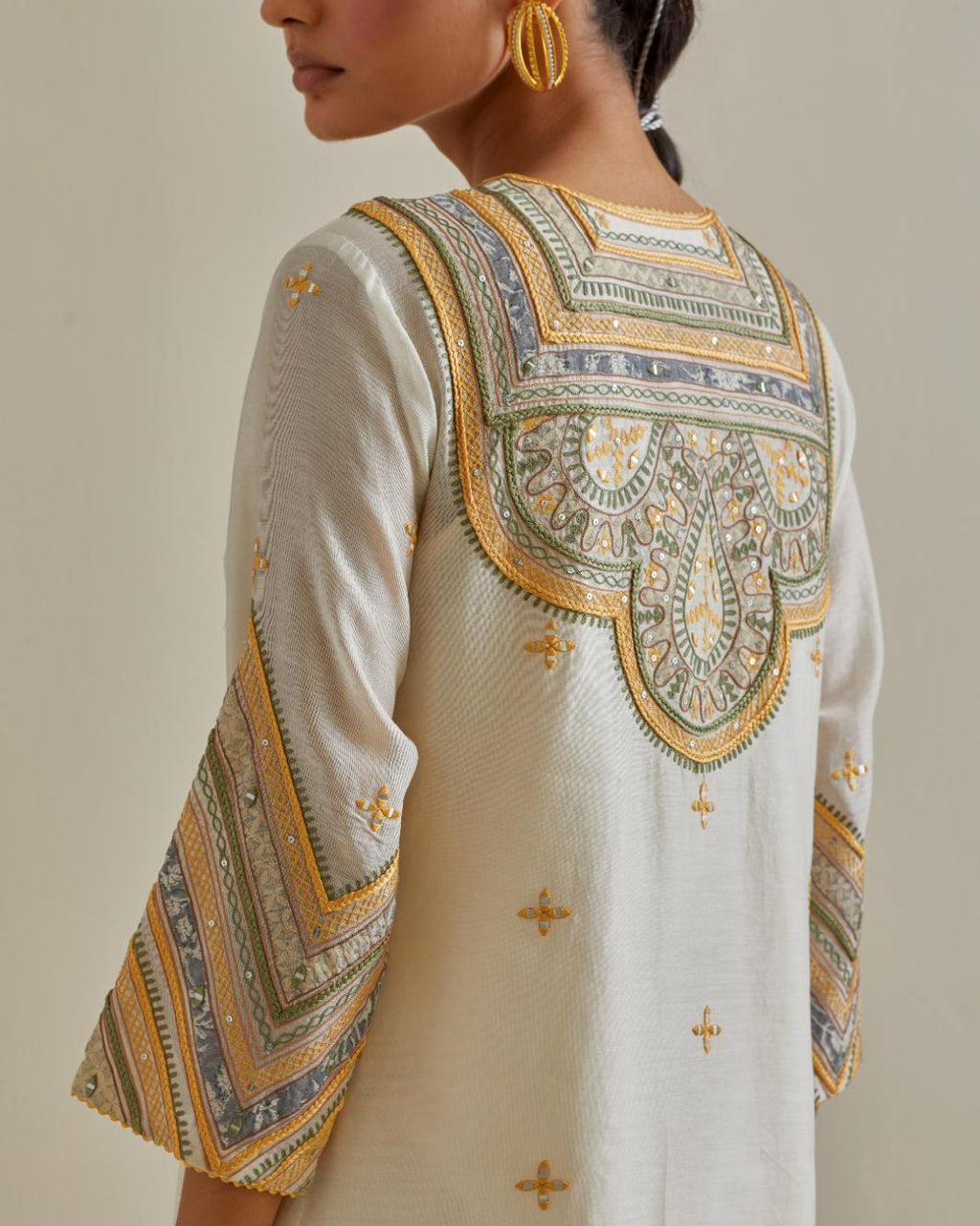Yellow and off-white cotton chanderi straight kurta set with patchwork and thread embroidery highlighted with mirrors, sequins, tassels and braids.