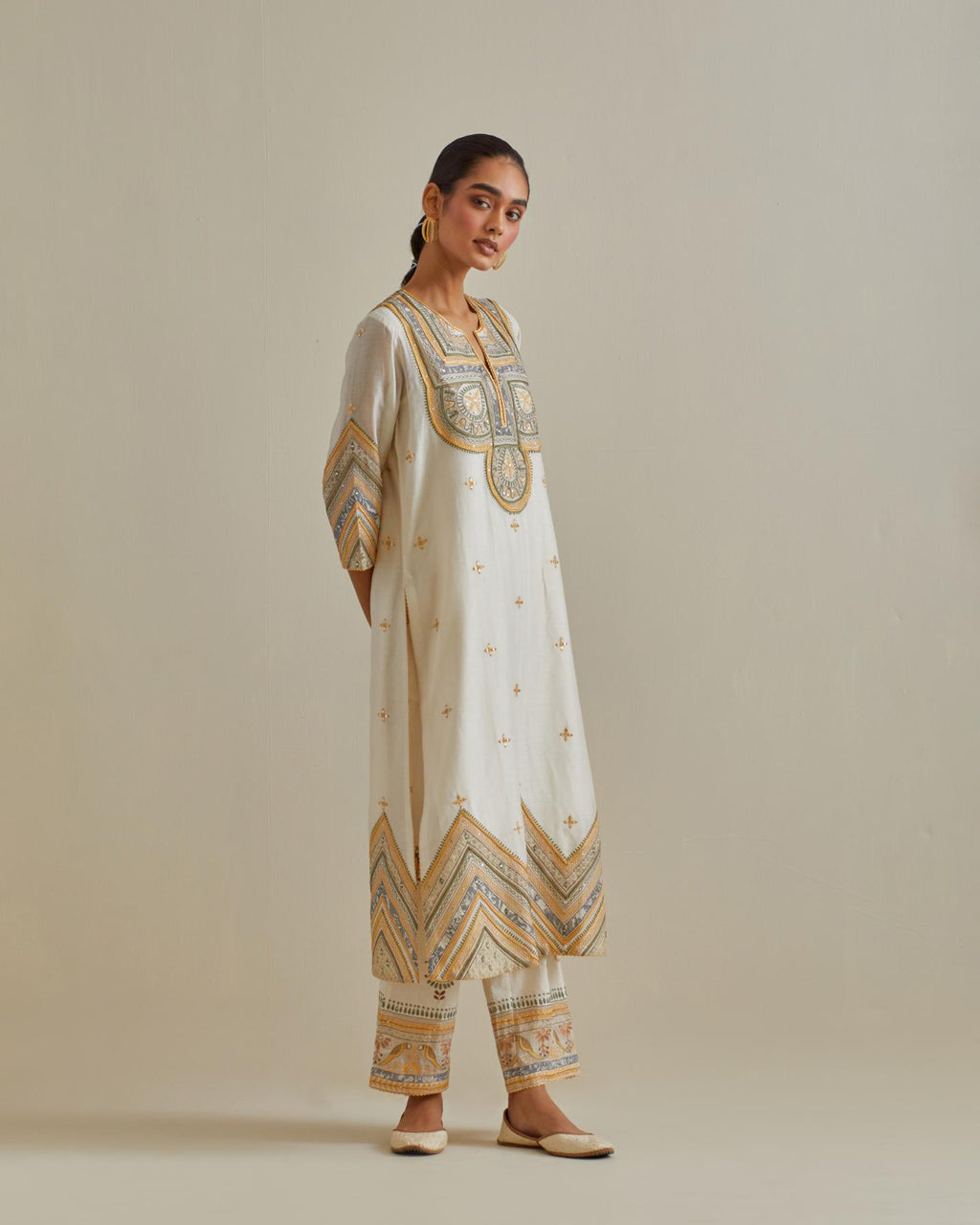 Yellow and off-white cotton chanderi straight kurta set with patchwork and thread embroidery highlighted with mirrors, sequins, tassels and braids.