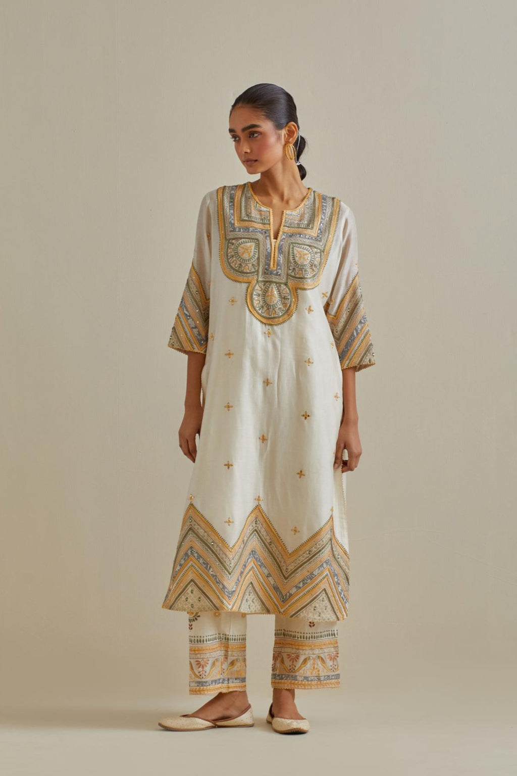 Yellow and off-white cotton chanderi straight kurta set with patchwork and thread embroidery highlighted with mirrors, sequins, tassels and braids.