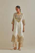 Yellow and off-white cotton chanderi straight kurta set with patchwork and thread embroidery highlighted with mirrors, sequins, tassels and braids.