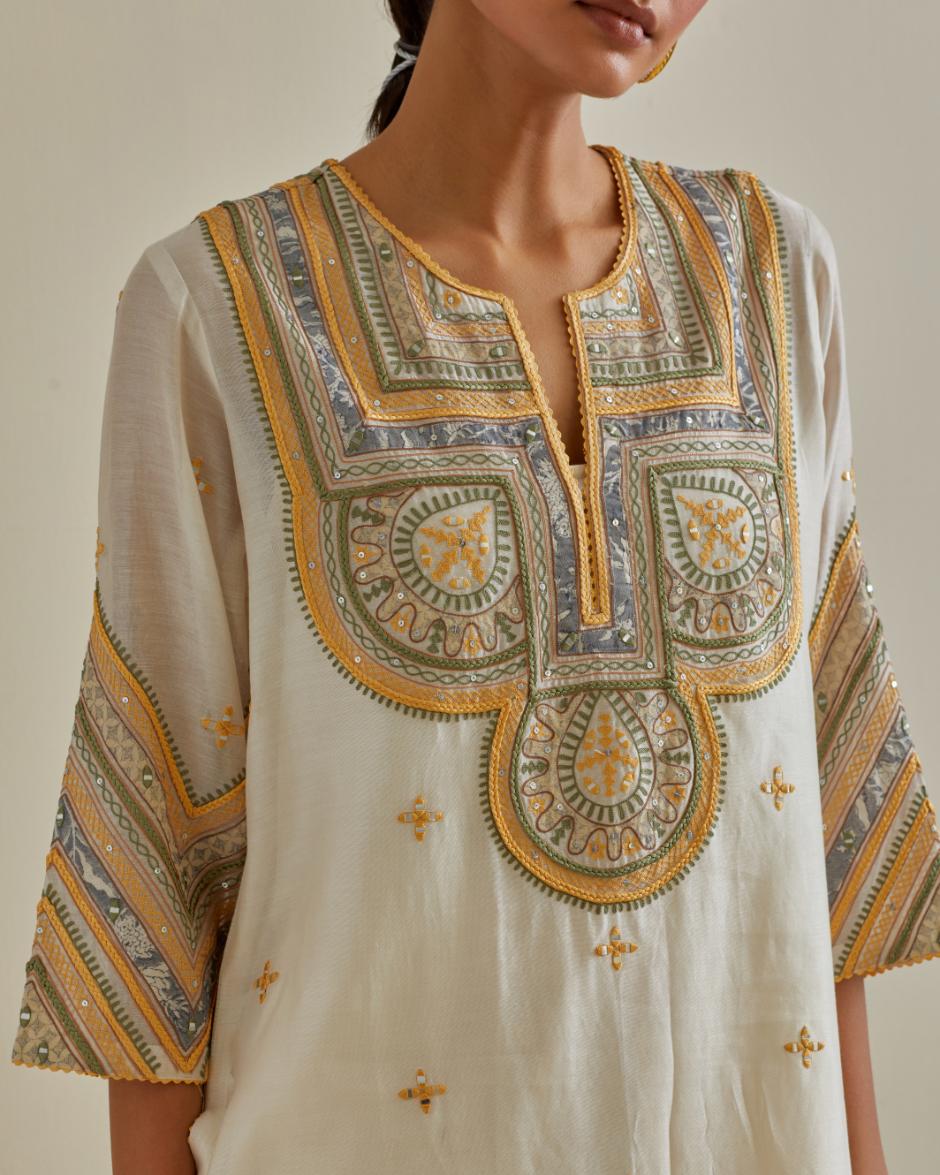 Yellow and off-white cotton chanderi straight kurta set with patchwork and thread embroidery highlighted with mirrors, sequins, tassels and braids.