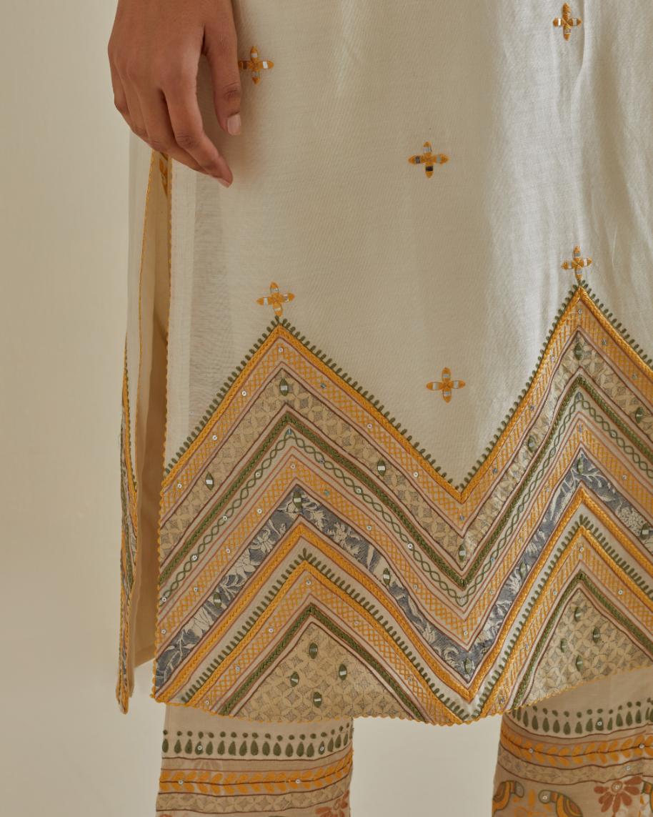 Yellow and off-white cotton chanderi straight kurta set with patchwork and thread embroidery highlighted with mirrors, sequins, tassels and braids.