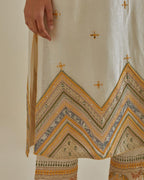Yellow and off-white cotton chanderi straight kurta set with patchwork and thread embroidery highlighted with mirrors, sequins, tassels and braids.