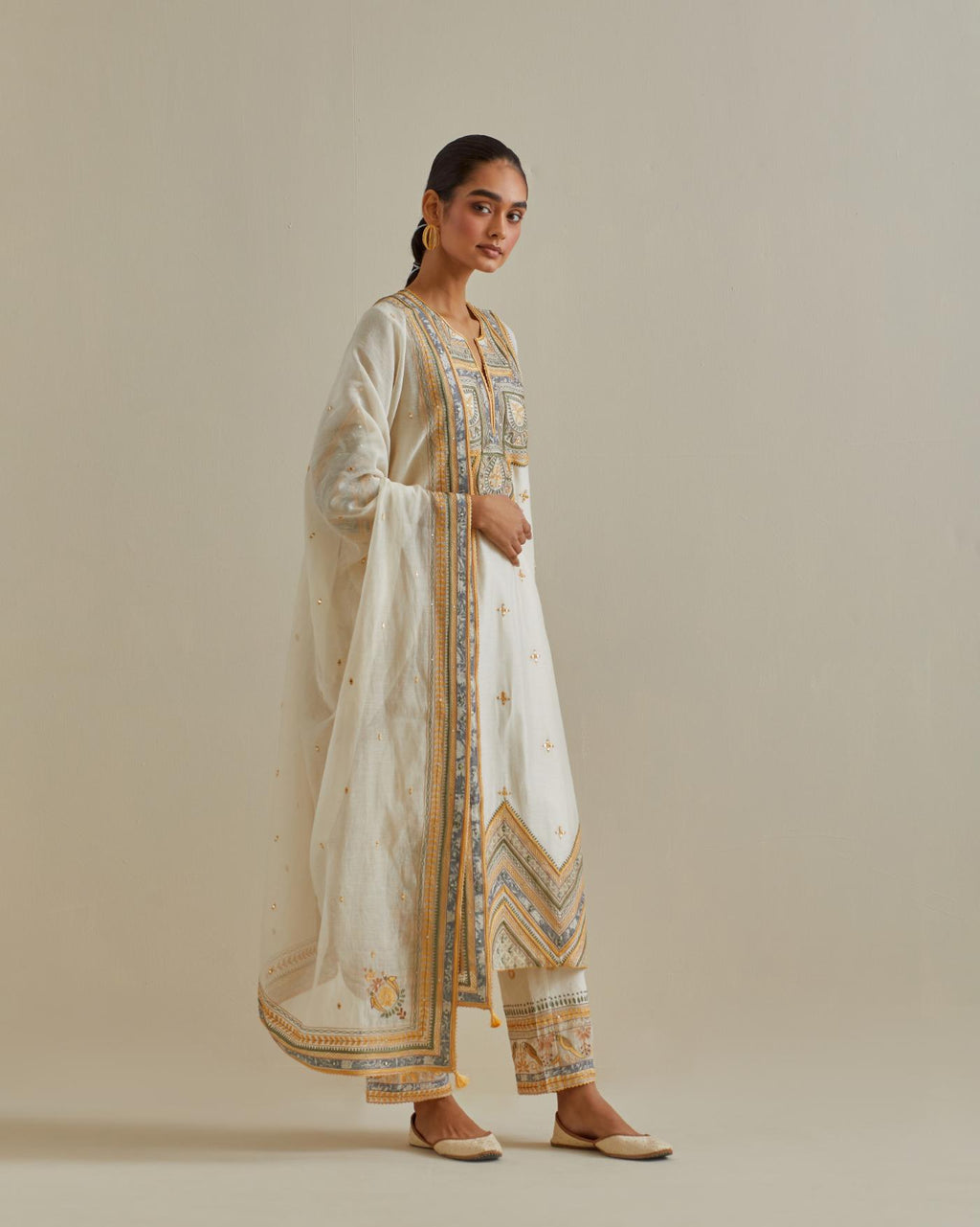 Yellow and off-white cotton chanderi straight kurta set with patchwork and thread embroidery highlighted with mirrors, sequins, tassels and braids.