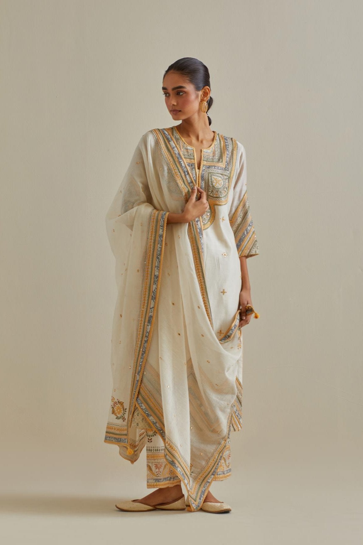 Yellow and off-white cotton chanderi straight kurta set with patchwork and thread embroidery highlighted with mirrors, sequins, tassels and braids.