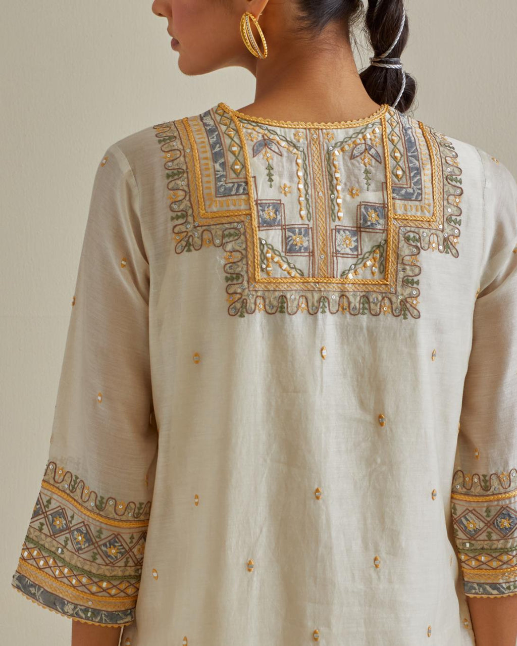 Yellow and off-white cotton chanderi straight kurta set with yoke with patchwork and silk thread embroidery highlighted with mirror, sequins, tassels and braids.