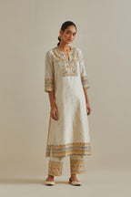 Yellow and off-white cotton chanderi straight kurta set with yoke with patchwork and silk thread embroidery highlighted with mirror, sequins, tassels and braids.